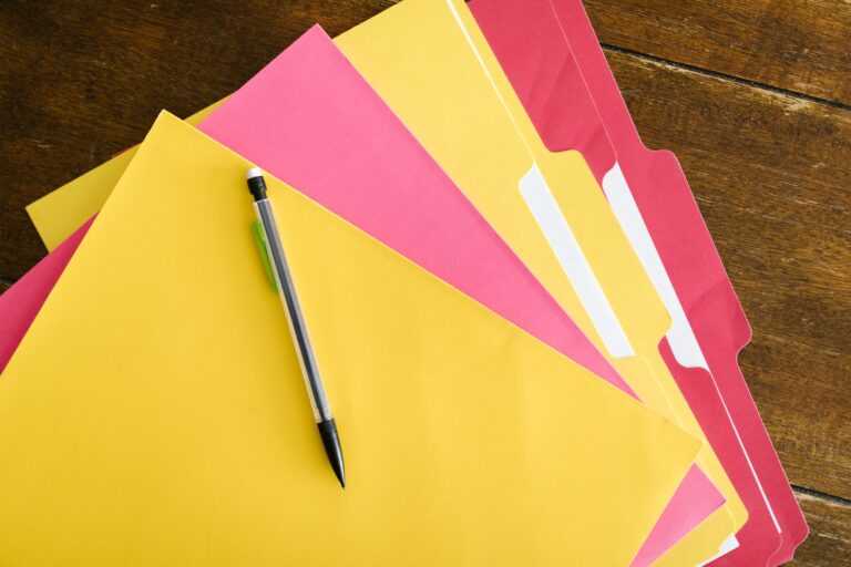 Wie farbcodierte Akten das Büro-Chaos killen Farbcodierte Akten – bunte Aktenmappen mit Stift auf einem Holztisch