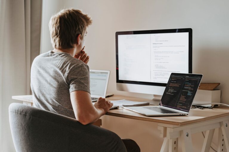 IT Infrastruktur für Startups: Die wichtigsten Tools und Systeme im Überblick IT-Infrastruktur für Startups – Entwickler arbeitet an mehreren Bildschirmen