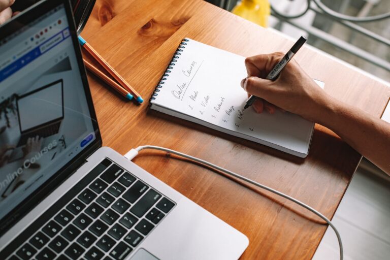 LMS-Anbieter für Startups – Person macht sich Notizen zu einem Onlinekurs am Laptop