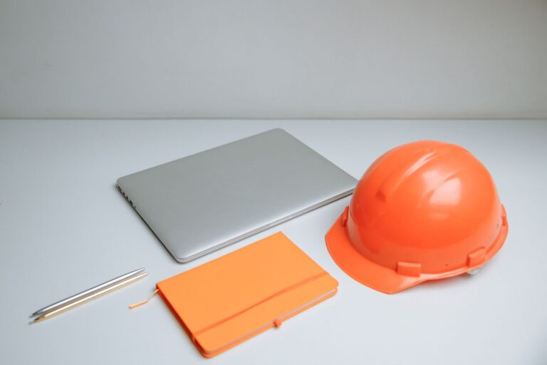Sicherheitstechnische Betreuung für Startups: Was Gründer:innen wissen sollten Sicherheitstechnische Betreuung für Startups – Schutzhelm, Laptop und Notizbuch auf dem Schreibtisch