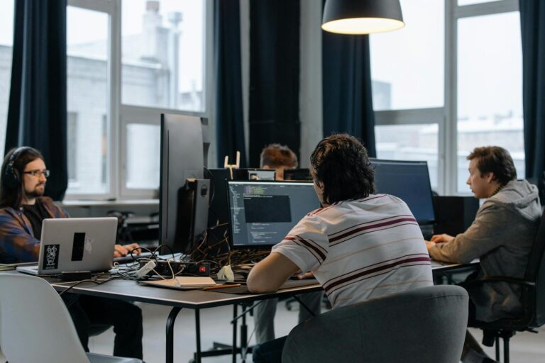 Entwicklerteam arbeitet gemeinsam an Computern in einem modernen Startup-Büro