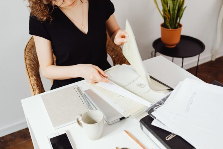 Schluss mit dem Papierchaos: Der sichere Weg zur digitalen Dokumentenverwaltung für Banken Digitale Dokumentenverwaltung – Frau sortiert Papierunterlagen am Schreibtisch
