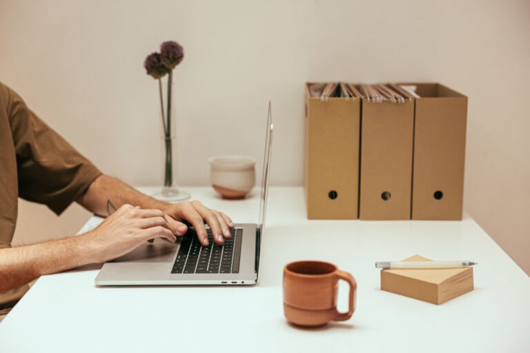 UG gründen – Gründer arbeitet am Laptop am aufgeräumten Schreibtisch mit Ordnern