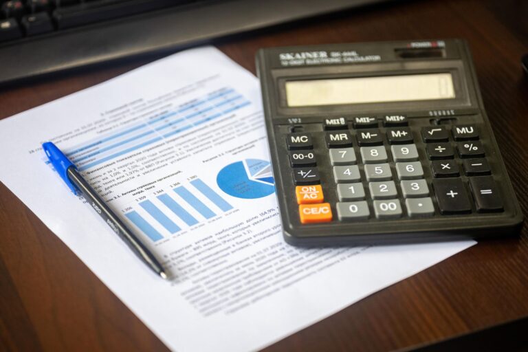 Umsatzsteuer für Gründer – Taschenrechner und Finanzbericht mit Diagrammen auf einem Schreibtisch