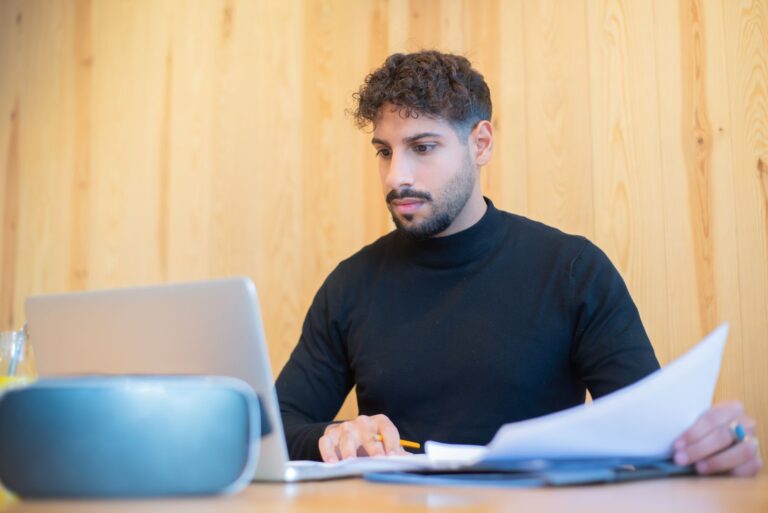 Gründungszuschuss – Gründer arbeitet mit Laptop und Unterlagen am Schreibtisch
