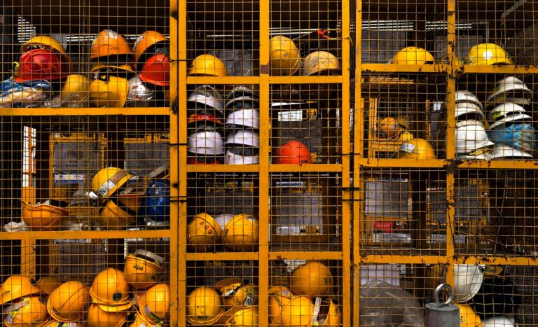 Arbeitsschutz im Start-up: Was mit den ersten Mitarbeitenden auf dich zukommt a rack filled with lots of yellow hard hats